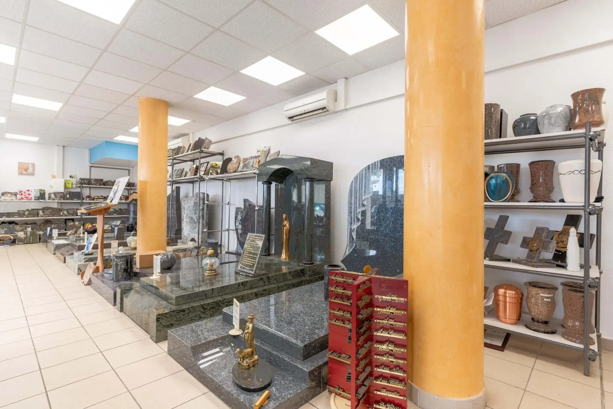 Vue d'ensemble du magasin d'exposition présentants des stèles, monuments et urnes funéraires.