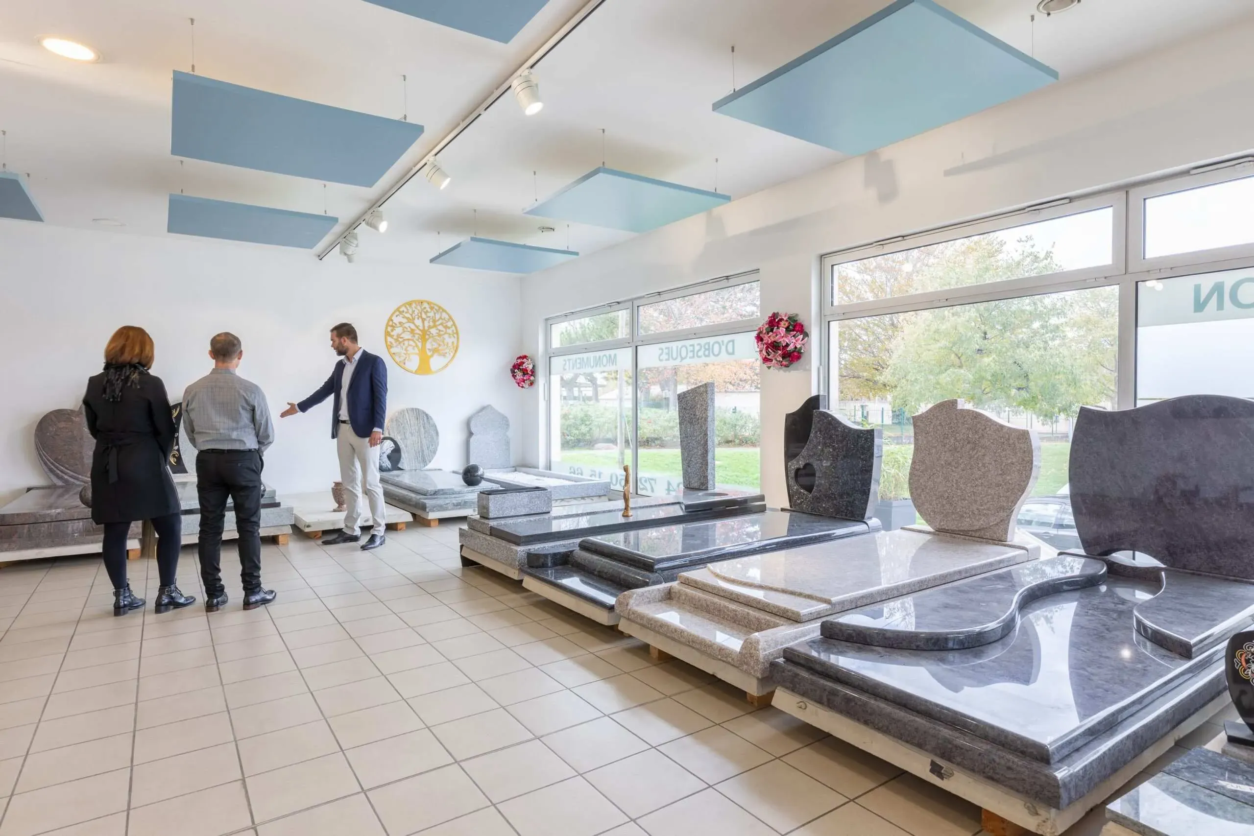 Conseiller présentant des monuments funéraires à un couple dans le showroom.