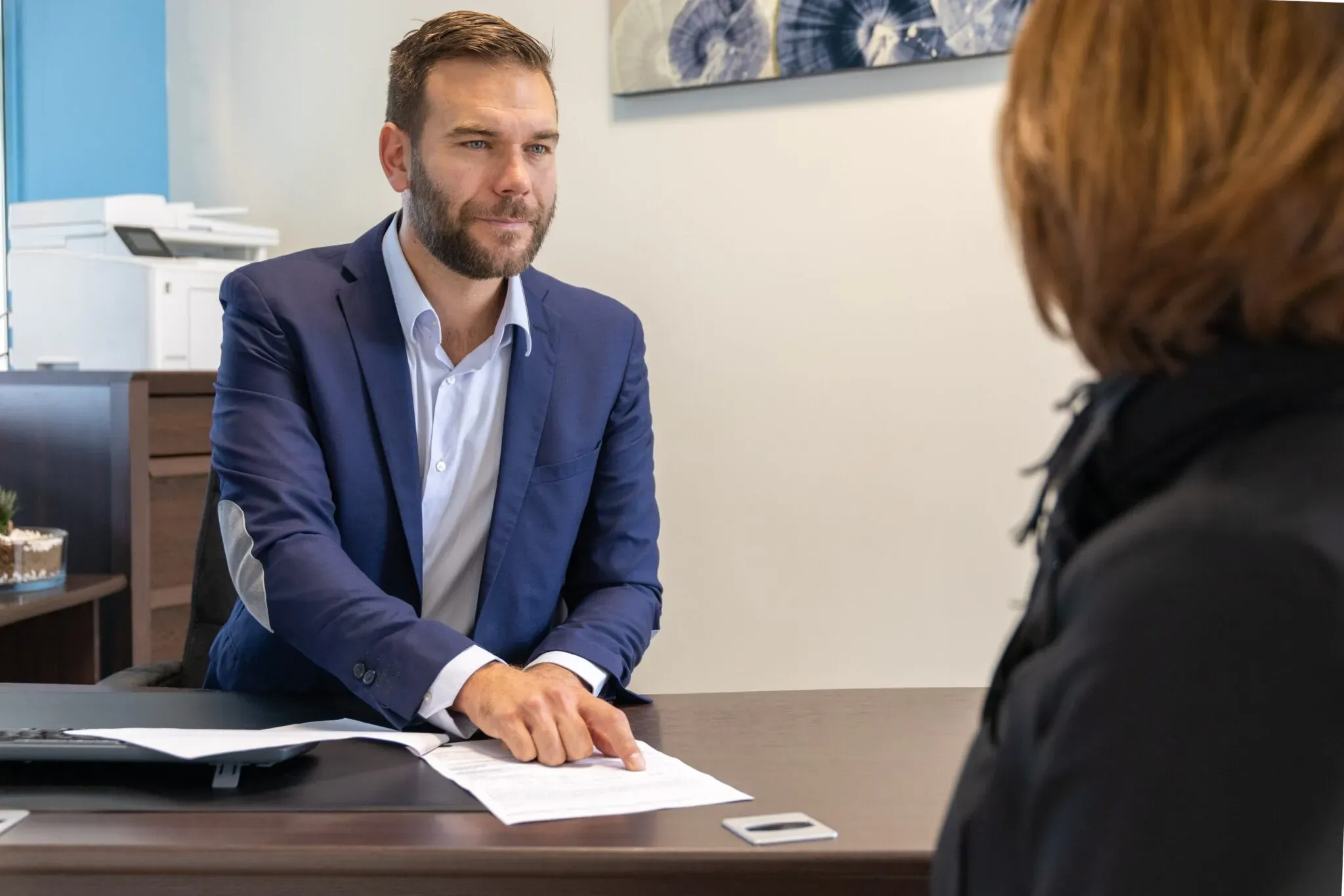 Conseiller funéraire expliquant un contrat ou un document à une cliente à son bureau.